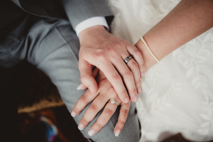 Man and woman with hands showing off engagement ring and wedding band